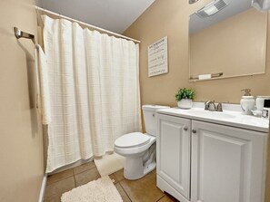 Ein Badezimmer mit Toilette, Duschvorhang, Waschbecken und Spiegel.