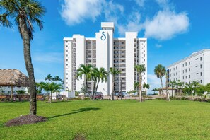 A multi-story hotel with a prominent 'S' logo, surrounded by palm trees and a well-maintained lawn. - 🏖️Beachfront, Pool and Stunning Sunsets | Sunset Condo 502🌅 (Fort Myers Beach)