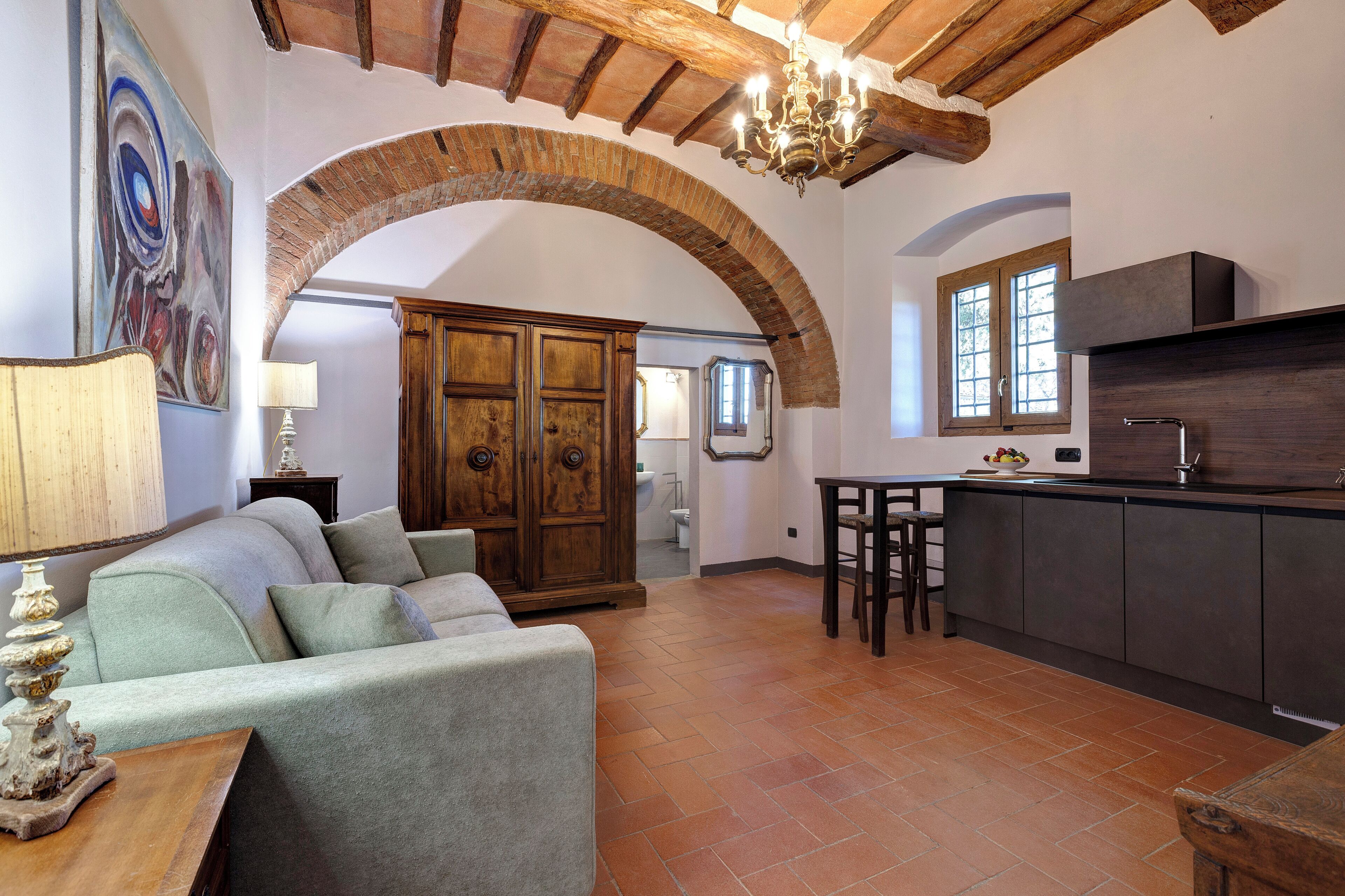 A spacious living area with a sofa, a wooden cabinet, and a kitchen area with a bar.