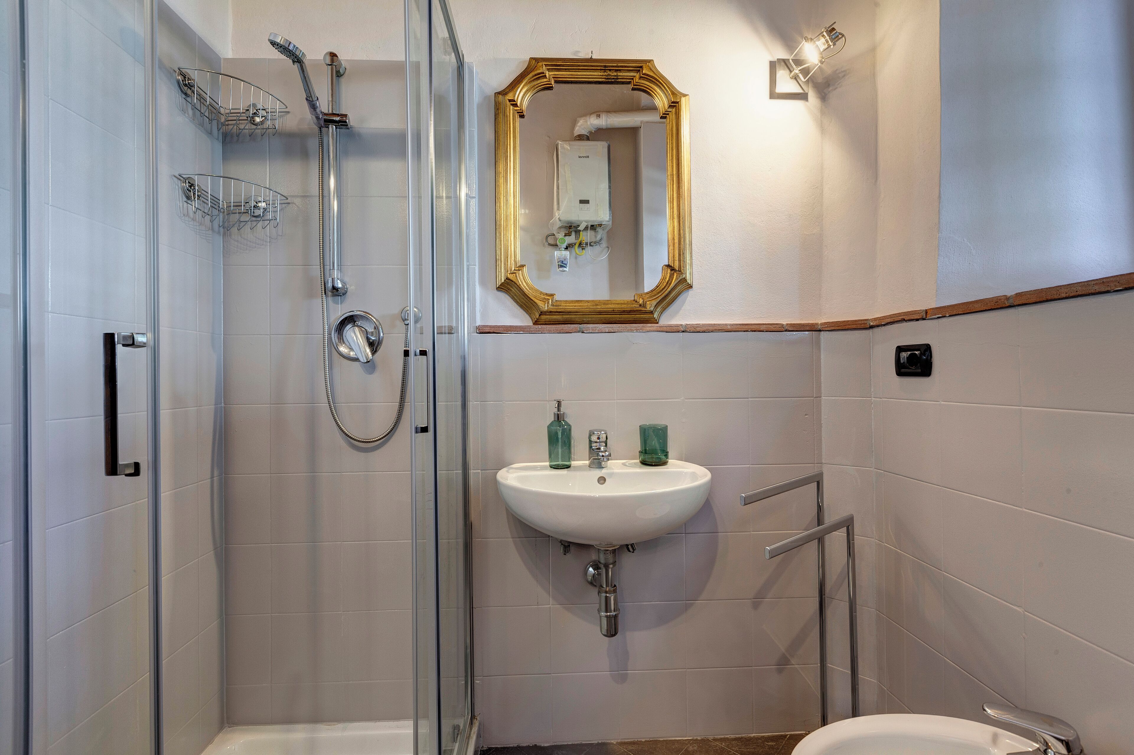 Ein Badezimmer mit Duschkabine, Waschbecken mit Spiegel darüber und Toilette.