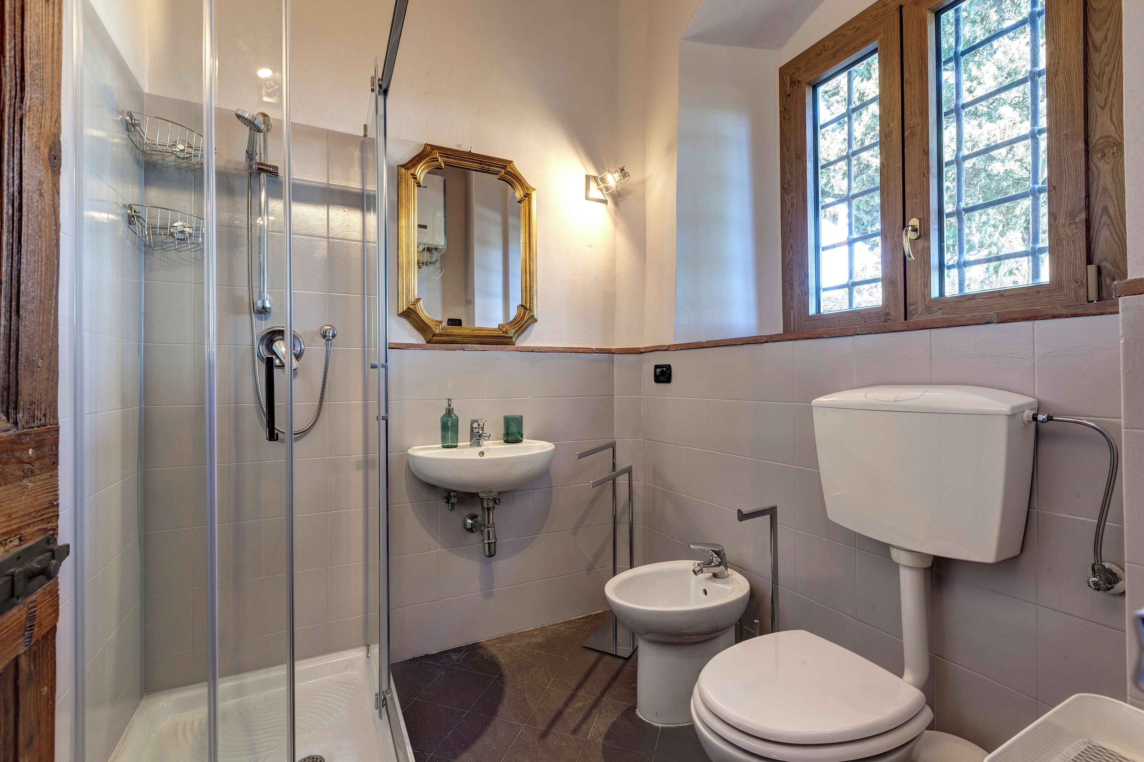 Une salle de bain comprenant une douche à parois de verre, un lavabo, un bidet et des toilettes.