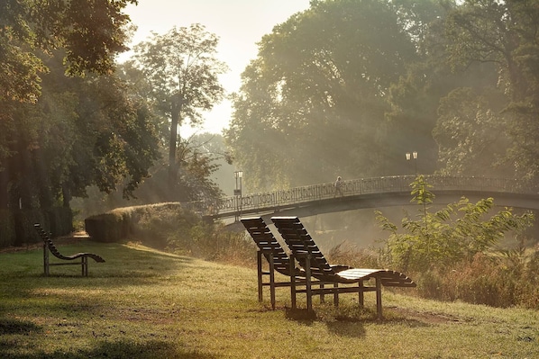 Un parque con un puente, bancos y un farol.