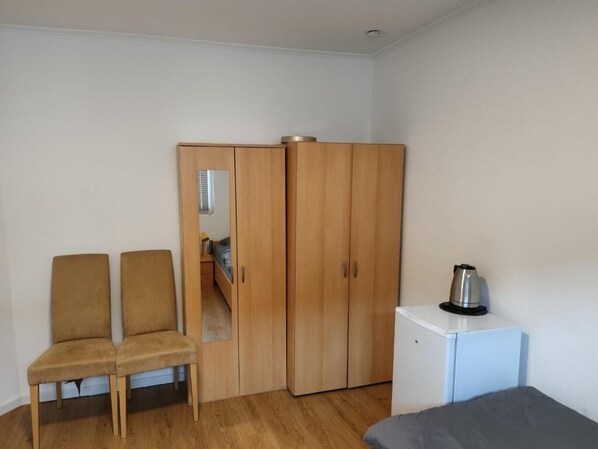 A room with a wardrobe, a small kitchenette, and two chairs. - Monteurzimmer Mühlheim am Main (Mühlheim)