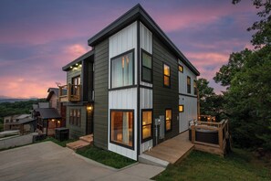 Uma casa de vários andares com varanda, janelas amplas e área de deck.