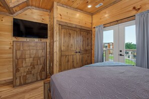 Quarto de madeira com cama, televisão e guarda-roupa.