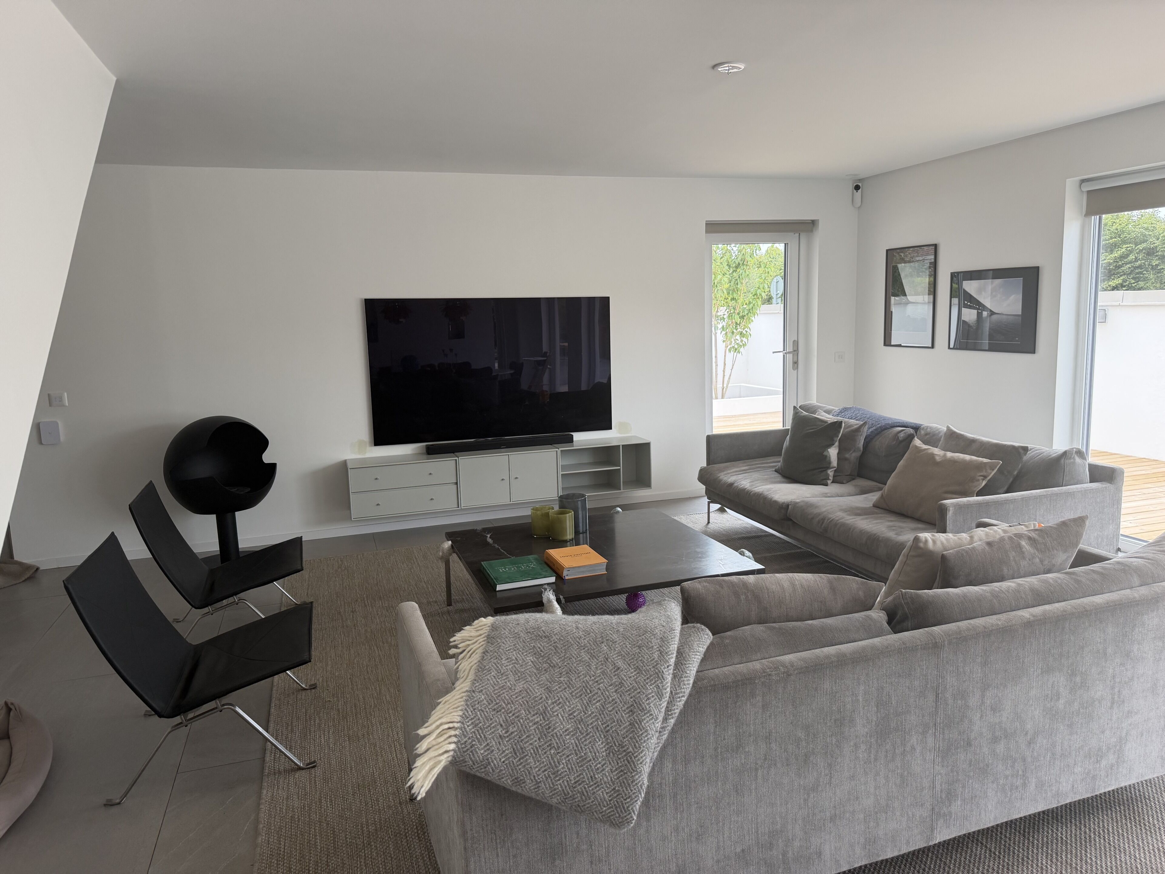 A modern living room with a flat-screen TV, grey sofa, and a coffee table.
