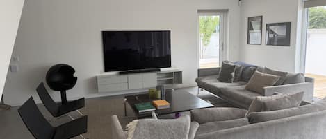 A modern living room with a flat-screen TV, grey sofa, and a coffee table.