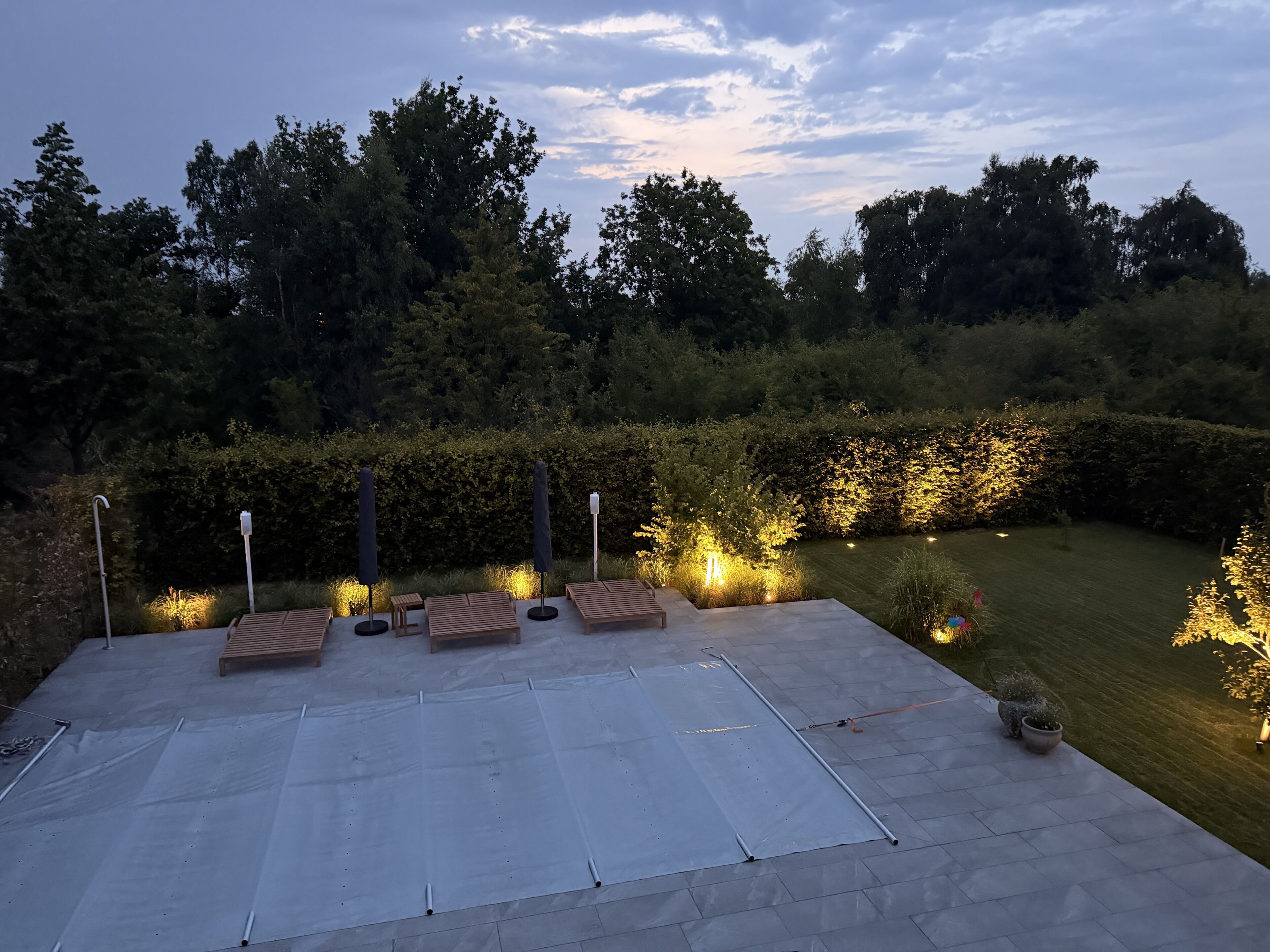 Ein möblierter Außenbereich mit Sitzgelegenheiten und Blick auf einen angelegten Garten.
