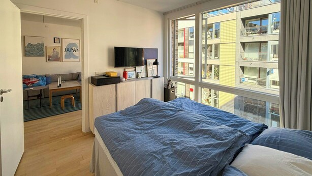 Une chambre à coucher avec un grand lit, une télévision et des œuvres d’art accrochées au mur.