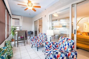 A room with a ceiling fan, a table with chairs, a sofa, a bed, and a view through a glass door. - Newly renovated 2B 2B Mid-Century Modern Condo with LARGE HEATED POOL (Clearwater)