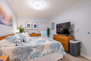 A bedroom with a bed, a TV, a dresser, and a trash bin. - Newly renovated 2B 2B Mid-Century Modern Condo with LARGE HEATED POOL (Clearwater)