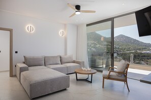 A modern living room with a sectional sofa, a round coffee table, and a single armchair. - Luxurious Villa Poseidon - With Private Pool (Bali)