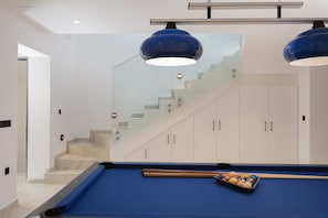 A modern interior with a pool table, a staircase, and a glass railing. - Luxurious Villa Poseidon - With Private Pool (Bali)