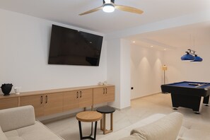 A modern living room with a pool table, a sofa, a cabinet, and a ceiling fan. - Luxurious Villa Poseidon - With Private Pool (Bali)