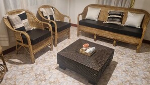A room with two wicker sofas, a small coffee table, and a patterned floor.