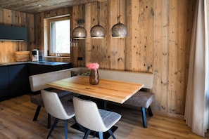 A wooden interior with a wooden table, two chairs, a bench, and pendant lights. - SLOW Fine Chalets (Neustift im Stubaital)