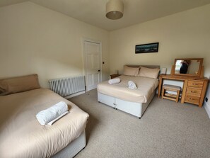 Ein Schlafzimmer mit zwei Betten, einem Schminktisch, einem Spiegel und einer Heizung.