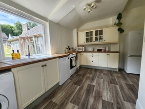 A kitchen with white cabinets, a wooden countertop, and a view of the outside. - Gorgeous Three Bedroom Home in Dunkeld (Birnam)