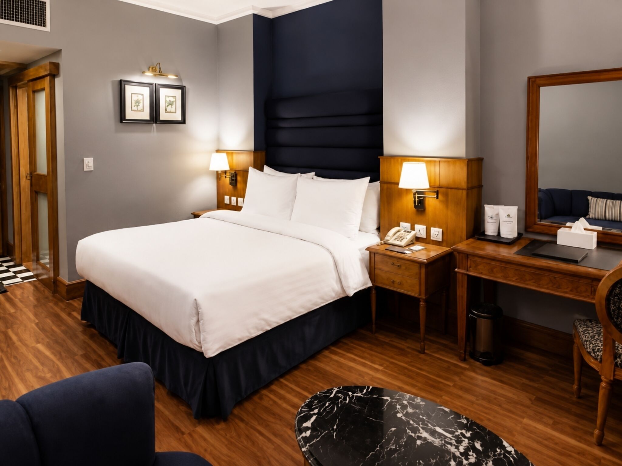Una habitación de hotel con cama, mesita de noche, escritorio, silla y una mesa redonda negra.
