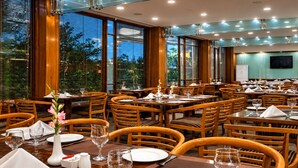 Un restaurante con varias mesas dispuestas para comer, con mobiliario de madera y amplios ventanales.