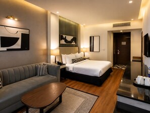 Quarto de hotel moderno com uma cama, um sofá, uma mesa de centro e uma televisão.