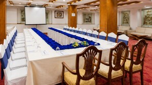 Un salón de conferencias con una larga mesa, sillas y una pantalla.