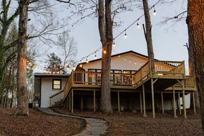 A two-story wooden cabin with a deck, surrounded by trees and a winding path. - Greenville Riverfront Escape w/ Hot Tub, Game Room, Sauna & River Access! (Greenville)