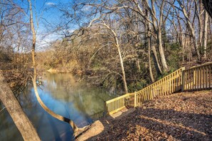 A wooden bridge over a calm river, surrounded by leafless trees and a clear sky. - Greenville Riverfront Escape w/ Hot Tub, Game Room, Sauna & River Access! (Greenville)