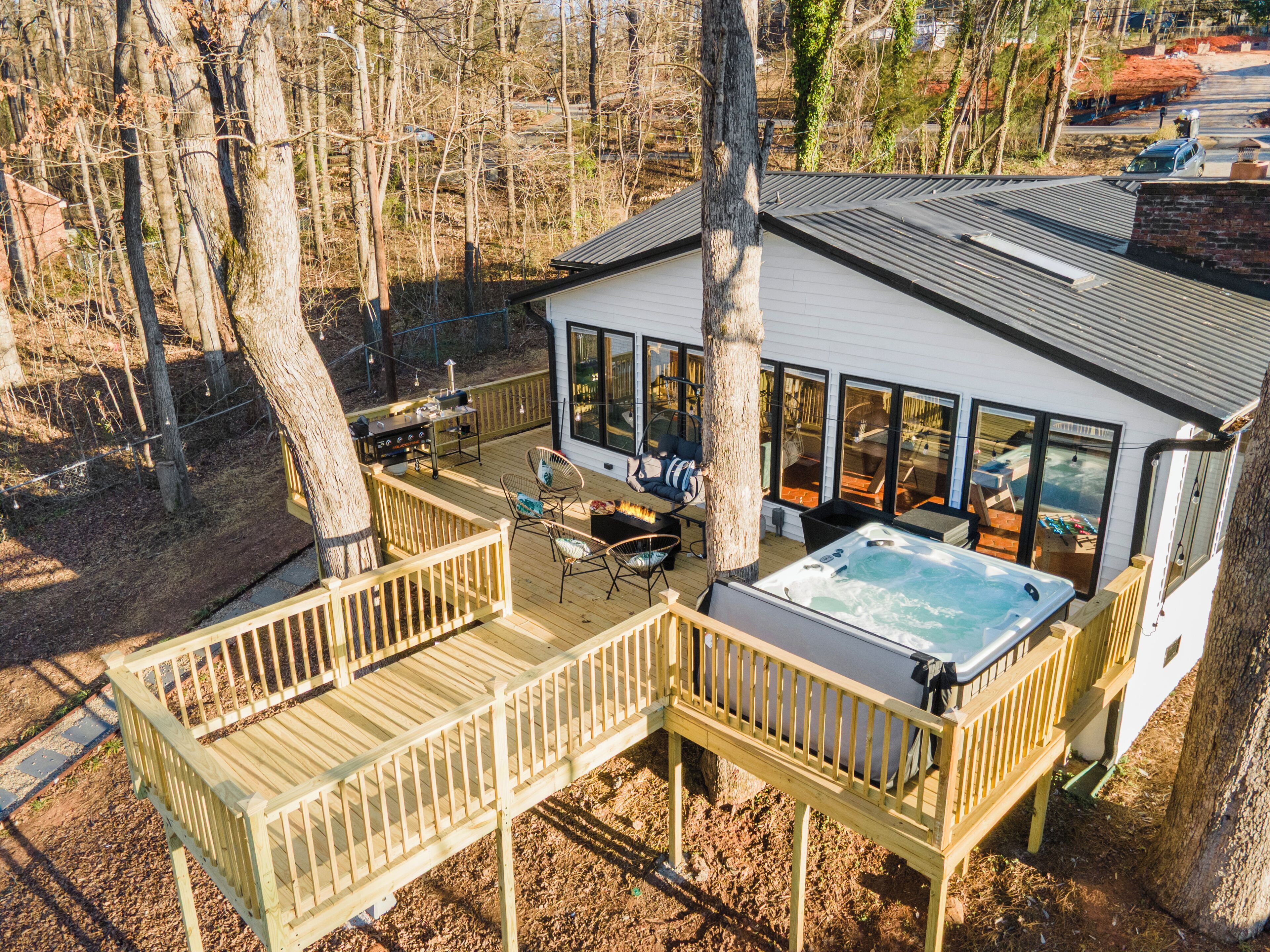 Une terrasse avec coin salon extérieur, un jacuzzi et une vue sur la zone boisée environnante.