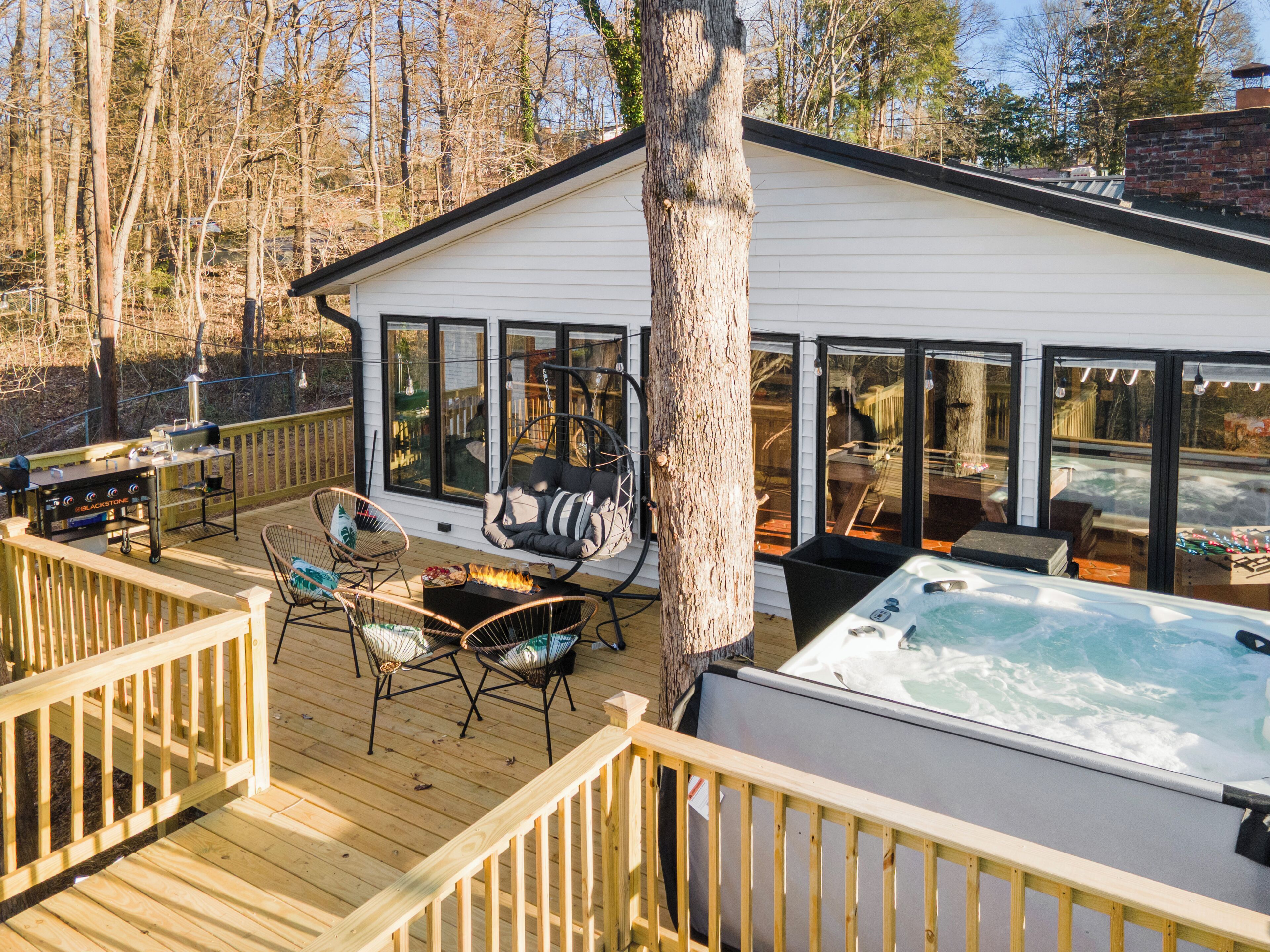 A deck with outdoor furniture, a hot tub, and a barbecue grill.
