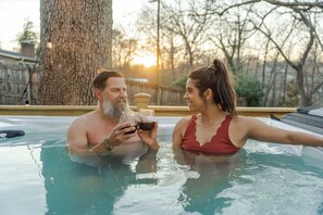 Two people in a hot tub with a tree and a fence in the background. - Greenville Riverfront Escape w/ Hot Tub, Game Room, Sauna & River Access! (Greenville)