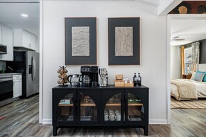 Eine moderne Küche mit einem schwarzen Schrank, der Kaffeugeräte und Tassen präsentiert.