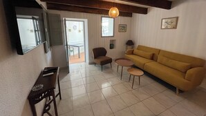 A living room with a sofa, a chair, a small table, and a TV on a stand. - A house in the heart of the village of Mourèze, just a stone's throw from the Cirque. (Mourèze)