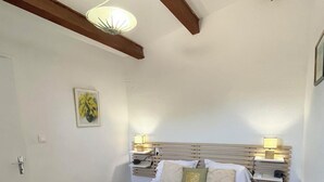 A bedroom with a bed, bedside tables, a wall-mounted light fixture, and a framed picture. - A house in the heart of the village of Mourèze, just a stone's throw from the Cirque. (Mourèze)