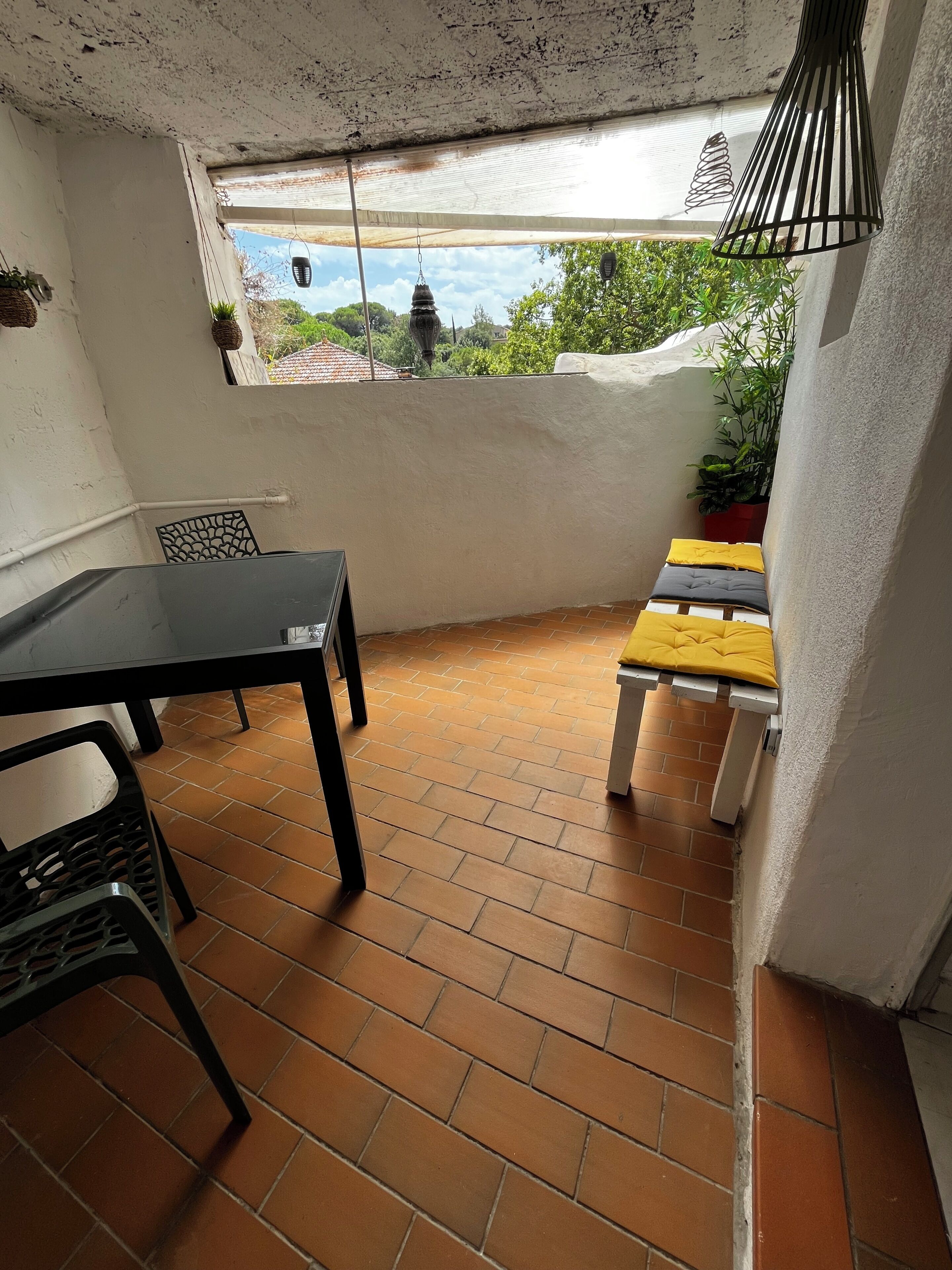 A patio area with a table and chairs, a small bench, and a potted plant.