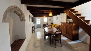 A dining area with a wooden table and chairs, a kitchen with wooden cabinets, and a staircase. - A house in the heart of the village of Mourèze, just a stone's throw from the Cirque. (Mourèze)