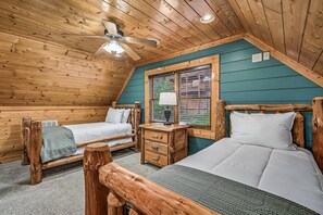 Ein gemütliches Ferienhäuschen mit zwei Holzbetten, einem Deckenventilator und einem Fenster mit Jalousien.