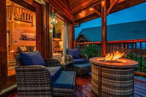 Eine Holzterrasse mit Korbmöbeln und einem Feuerkorb in der Mitte.