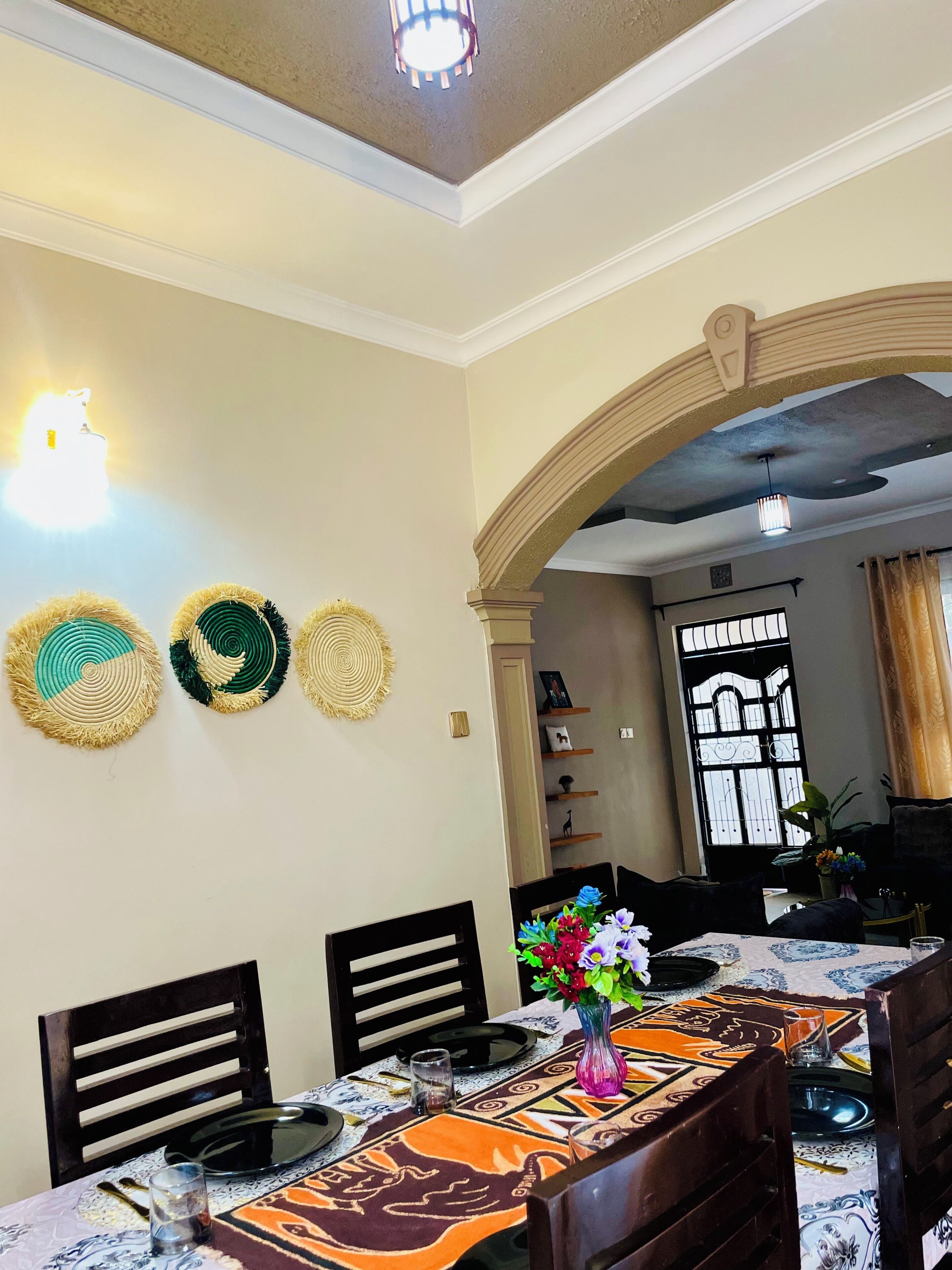 A dining area with a table set for four, chairs, and a decorative wall with woven items.