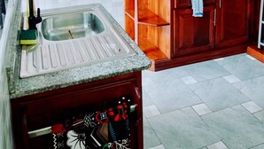 A kitchen with a granite countertop, a sink, wooden cabinets, and a microwave.