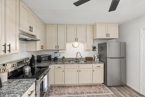 A kitchen with light-colored cabinets, a stainless steel refrigerator, a microwave, a stove, and a sink. - Durham Home Near Duke-Fast WiFi & Self Check-In (Durham)