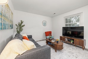A modern living room with a grey sofa, a coffee table, and a TV on a wooden stand. - Durham Home Near Duke-Fast WiFi & Self Check-In (Durham)