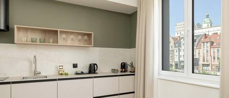 A modern kitchen with a built-in oven, a coffee maker, and a window with a city view.