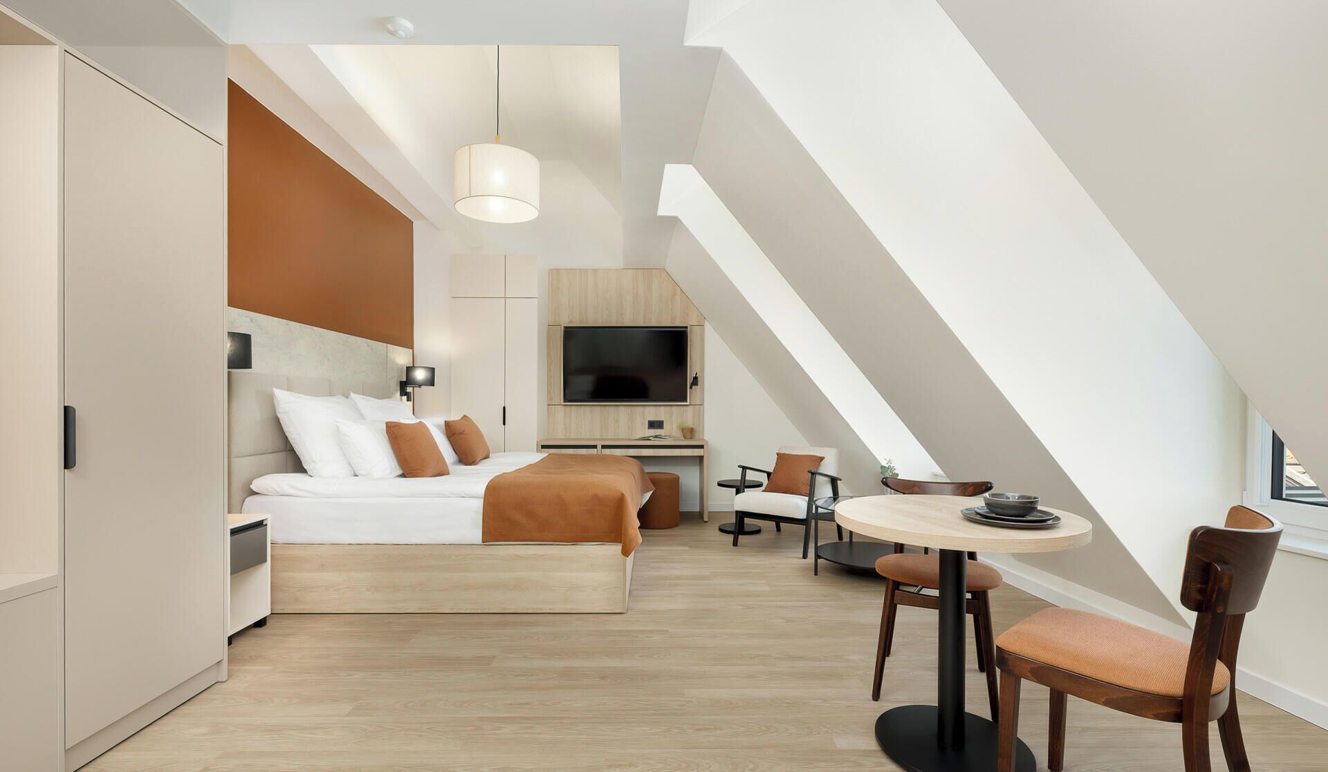 Une chambre d’hôtel moderne équipée d’un lit, d’un bureau, d’une télévision et d’un coin repas.
