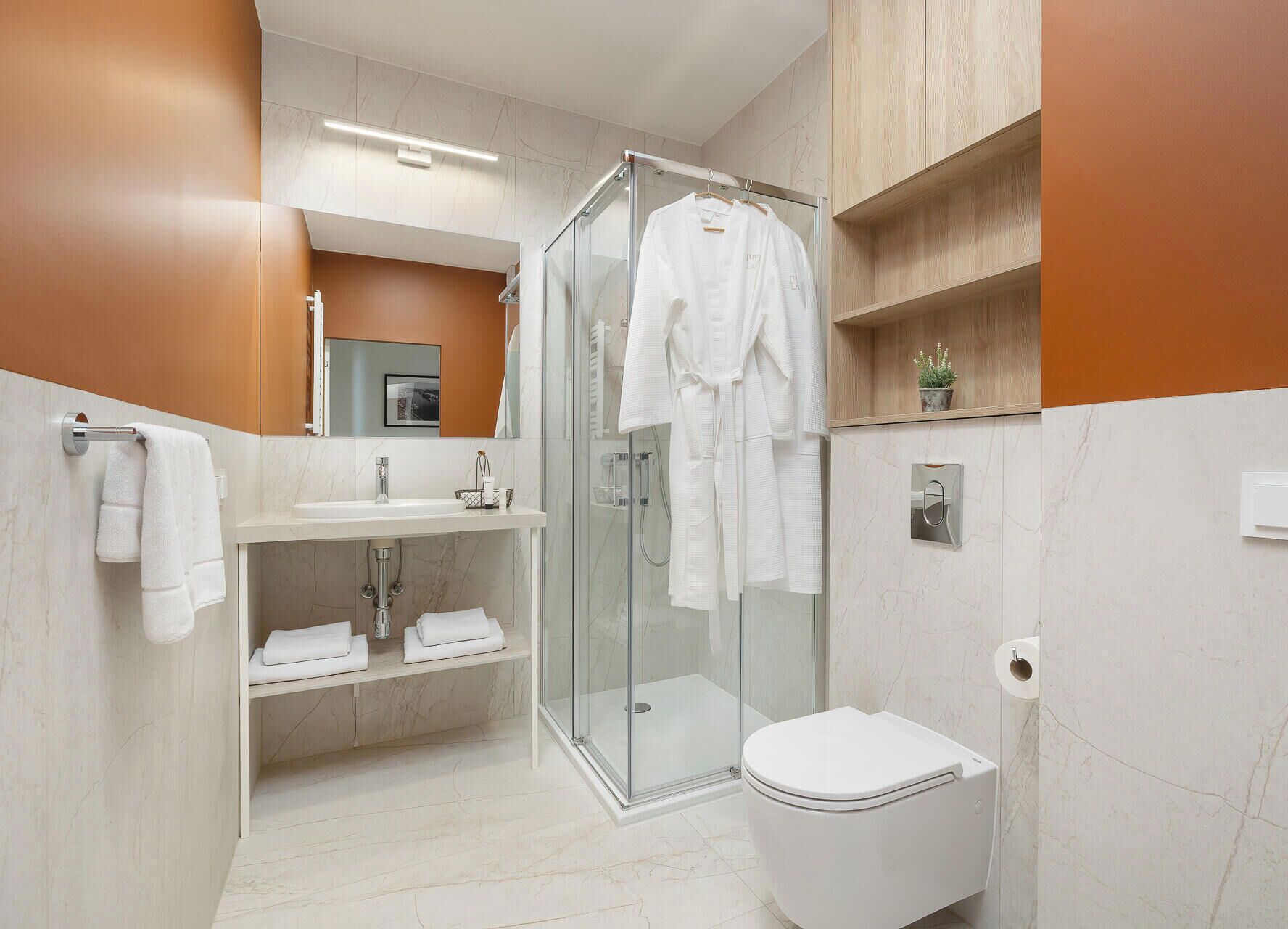 Un baño moderno con cabina de ducha de vidrio, inodoro blanco y tocador con espejo y lavabo.
