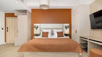 A modern hotel room with a large bed, a TV, and a desk.