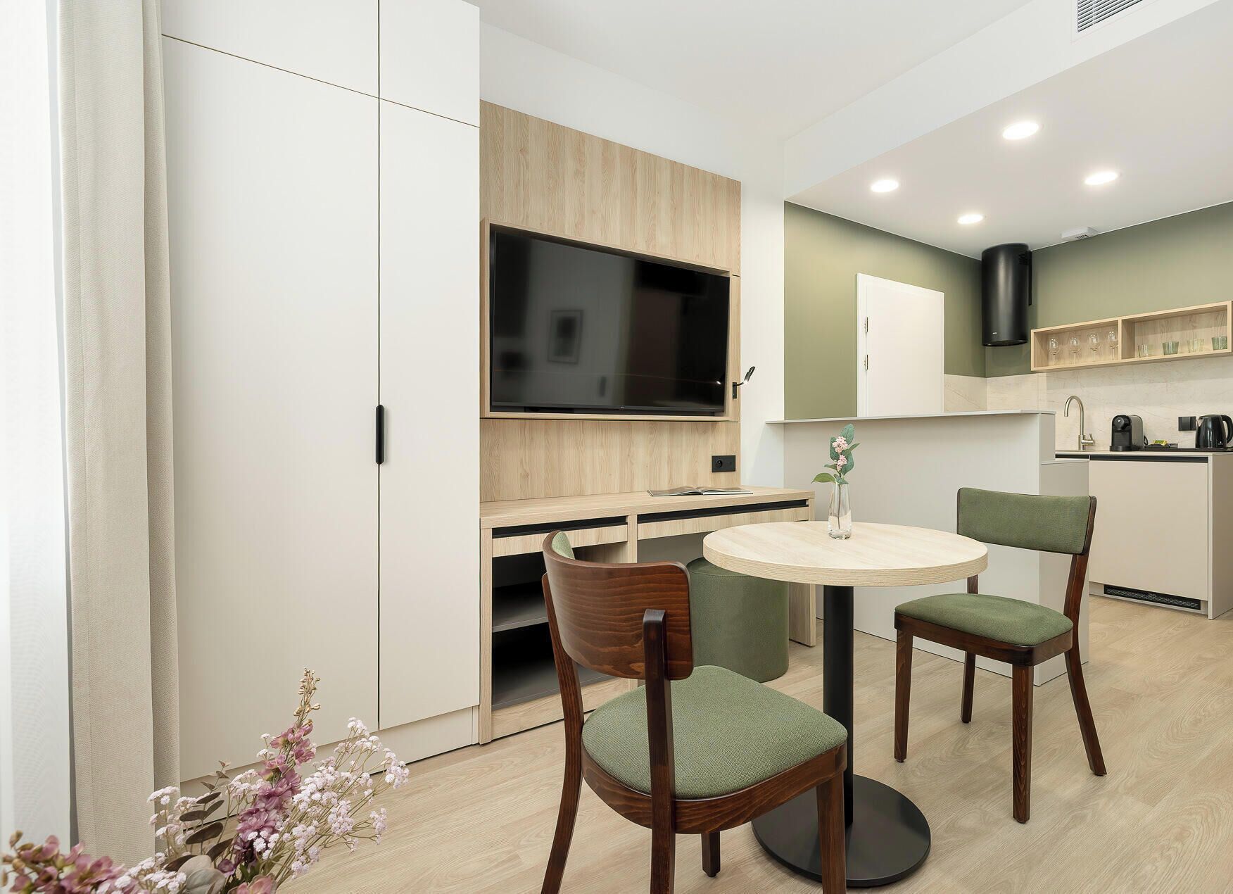 Een moderne keuken met een ingebouwde televisie, een eethoek met twee stoelen en een kleine tafel.