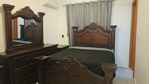 A bedroom with a wooden bed, a dresser, a mirror, and a patterned curtain. - Center of esperanza 3 bedroom plus pool, a/c and hot water fits 12 people comfy. (Esperanza)