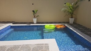 A swimming pool with two potted plants, a green and an orange inflatable ring, and a tiled border. - Center of esperanza 3 bedroom plus pool, a/c and hot water fits 12 people comfy. (Esperanza)