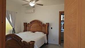 Ein Schlafzimmer mit einem hölzernen Bett, einem Deckenventilator und einem Fenster mit Vorhängen.